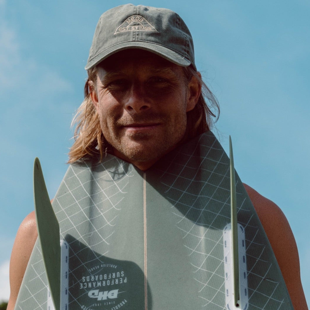 Person holding a surfboard with a clear blue sky in the background